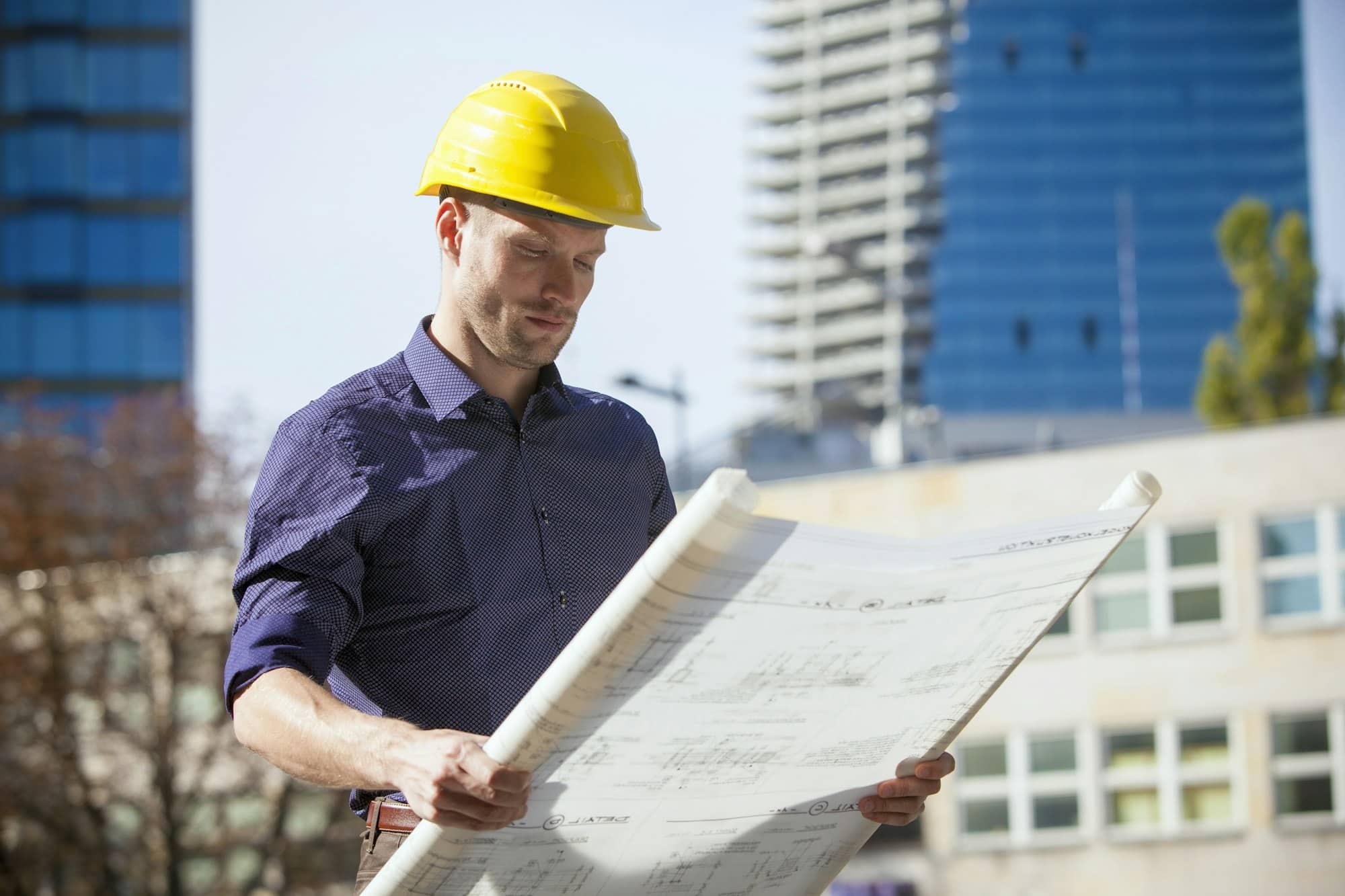 Building contractor wearing hard hat looking at blueprint