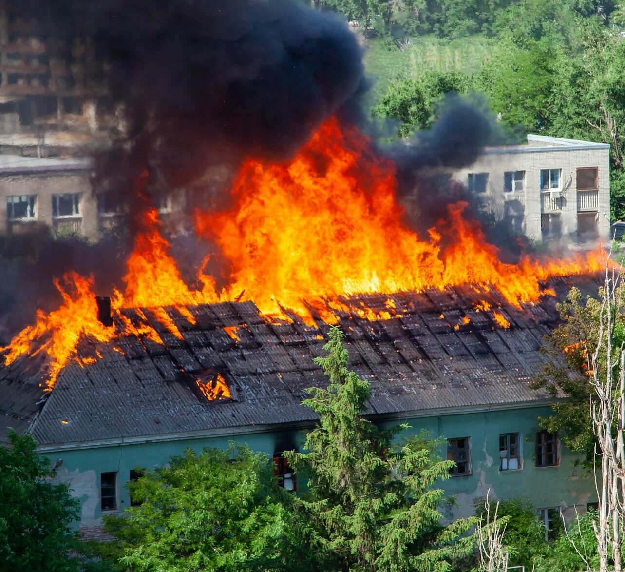 A fire in an old abandoned house, a view from the window of a neighboring high-rise building.
