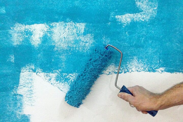 Painting the wall with blue paint and a roller. Renovation concept.