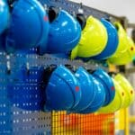 safety helmets of different colors on a rack in a factory, the concept of safety against injuries at