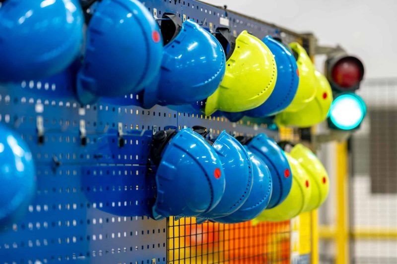 safety helmets of different colors on a rack in a factory, the concept of safety against injuries at